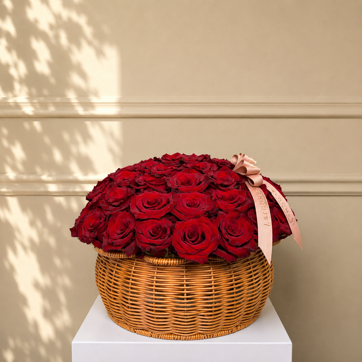 Basket of red roses with a pink ribbon on a beige background